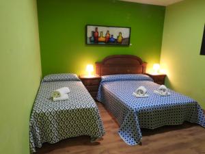 Villa Paraiso في Villacañas: سريرين في غرفة بجدران خضراء
