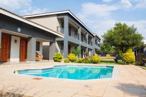 a villa with a swimming pool in front of a house at Zamambongi Guest Houses & Spa in Newcastle