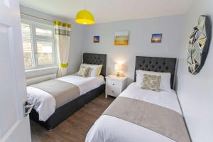 - 2 lits dans une chambre aux murs blancs dans l'établissement Sandbanks Braunton, Stylish Cottage near to Saunton Beach Sleeps 4, à Croyde