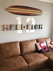 ein braunes Sofa im Wohnzimmer mit einem Surfbrett an der Wand in der Unterkunft Seedeich in Cuxhaven