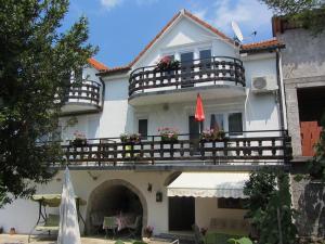 Cette maison blanche dispose d'un balcon et d'une terrasse. dans l'établissement Apartments Marijana, à Sršići