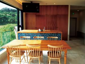 a dining room with a wooden table and chairs at CHULAX OKINAWA YOMITAN【Designer Condominium Hotel】 in Yomitan