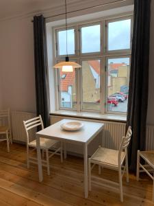 una mesa y sillas blancas en una habitación con ventana en Anne's Home Sønderbro, en Horsens