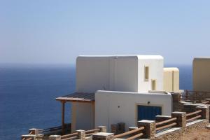 a white building with the ocean in the background at Monolithos Villas in Kipri