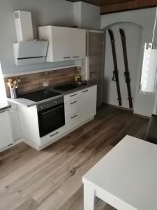 eine Küche mit weißen Schränken und einem Herd mit Backofen in der Unterkunft Ferienwohnung Familie Kowarik in Kurort Oberwiesenthal