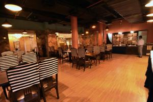 a dining room with tables and chairs and a man standing in the background at The Mark Hotel in Kolkata