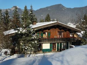 uma casa coberta de neve em frente a uma montanha em Le Bois des Louison em Seytroux