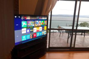 TV de pantalla plana en la sala de estar con ventana en Spectacular Lake and Ocean View Holiday Home en Lake Heights