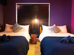two beds in a room with purple walls and a window at CHULAX OKINAWA YOMITAN【Designer Condominium Hotel】 in Yomitan