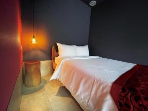 a bedroom with a white bed and a lamp at CHULAX OKINAWA YOMITAN【Designer Condominium Hotel】 in Yomitan