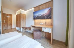 a bedroom with a bed and a tv on a wall at Am Mitteregghof in Saalbach Hinterglemm