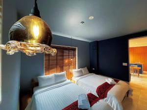 a bedroom with two beds and a chandelier at CHULAX OKINAWA YOMITAN【Designer Condominium Hotel】 in Yomitan