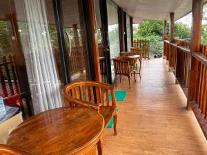 a porch with wooden tables and chairs and windows at RedDoorz Plus @ Puncak Mas Cottage in Lampung