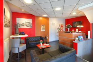 a waiting room with red walls and leather chairs at Cit'Hotel Atlantic Hotel in Pau