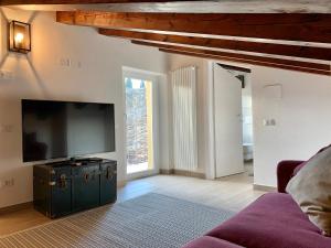 Una sala de estar con televisión y un sofá. en Casa La Margherita, en Desenzano del Garda