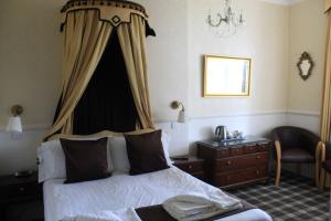 a bedroom with a bed and a dresser and a window at Headlands Hotel in Llandudno
