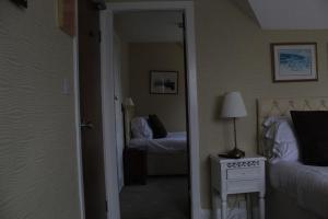 a bedroom with two beds and a hallway with a mirror at Headlands Hotel in Llandudno