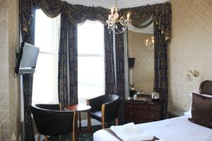 a hotel room with a bed and a desk and a window at Headlands Hotel in Llandudno