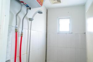 a shower in a bathroom with red and white tiles at 77 Guest House Serpong Mitra RedDoorz in Jakarta