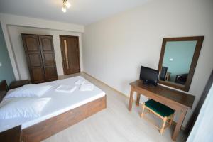 um quarto com uma cama, uma secretária e um espelho em Tuya Residence em Eforie Nord