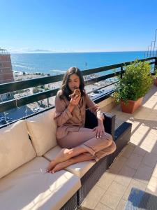 una mujer sentada en un banco cerca de la playa en Mareluna Penthouse - Luxury Suites en Salerno