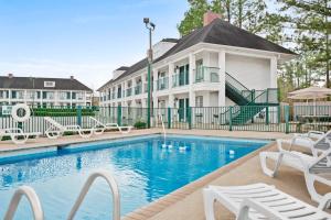 - une piscine en face d'une maison avec des chaises blanches dans l'établissement Days Inn by Wyndham Americus, à Americus