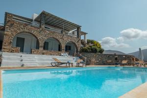 a villa with a swimming pool in front of a house at Terra in Parikia