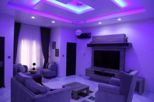 un salon avec éclairage violet et télévision dans l'établissement Rhodabode Apartments. A Luxury 3 bedroom bungalow., à Abuja