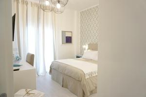 a white bedroom with a bed and a chandelier at Nodo Margherita in Bari