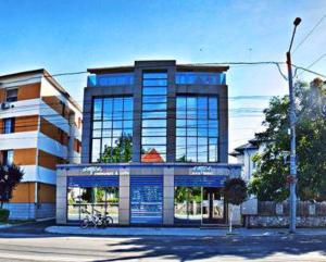 een groot gebouw met blauwe ramen aan een straat bij Hotel Aqua in Târgu Jiu