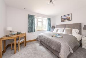 a bedroom with a bed and a desk and a bed and a table and chair at Wyndthorpe Cottage in Milton Abbas