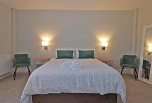 a bedroom with a large white bed with two green chairs at No.31 Castle Gate in Newark upon Trent