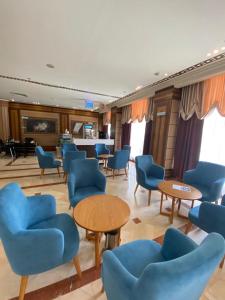 a waiting room with blue chairs and tables at Mirage Al Salam Hotel in Al Madinah