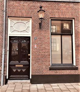 um edifício de tijolos com uma porta preta e duas janelas em De Buurvrouw Nr.18 em Doesburg