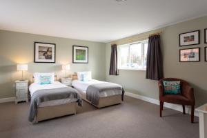 a bedroom with two beds and a chair and a window at The Plough in Wangford