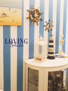 una mesa con un faro y un reloj en la pared en Loving Salento, en Porto Cesareo