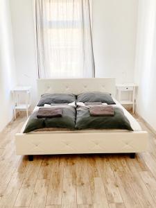 1 cama blanca en un dormitorio con suelo de madera en LUXURY apartment in the centre with a place for barbecue party, en Budapest