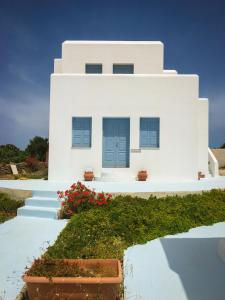 Casa blanca con puertas azules y flores rojas en Anatoli en Ano Meria