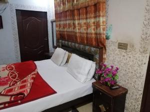 a bedroom with a bed and a vase of flowers on a table at Faizan Hotel in Lahore