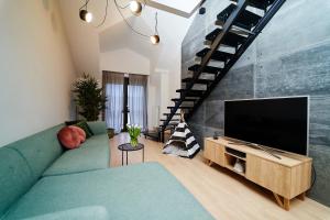 een woonkamer met een blauwe bank en een flatscreen-tv bij LOFT Apartment in Suwałki