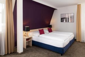 a bedroom with a large bed with white sheets and red pillows at Boutique Hotel Societe in Baden-Baden