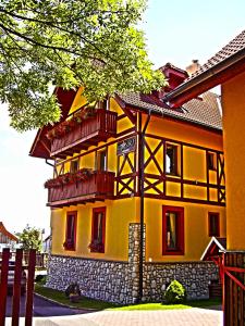 una casa gialla con balconi rossi sul lato di Penzion Bado a Stará Lesná