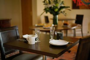 una mesa de madera con platos y vasos. en Glenburn Galgorm Bed & Breakfast, en Galgorm