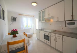 eine Küche mit weißen Schränken, einem Tisch und einem Esszimmer in der Unterkunft Apartment Leticija near city center in Poreč