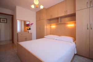 Schlafzimmer mit einem großen weißen Bett und Holzschränken in der Unterkunft Apartment Leticija near city center in Poreč