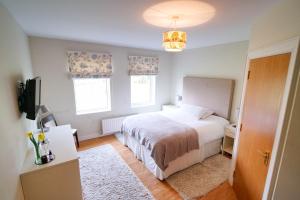 Schlafzimmer mit einem Bett, einem TV und Fenstern in der Unterkunft Glenburn Galgorm Bed & Breakfast in Galgorm