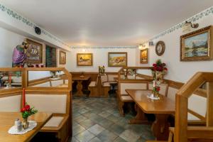 a restaurant with wooden tables and benches and paintings on the walls at Jagodic Garni Hotel in Cerklje na Gorenjskem +46 photos