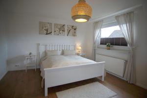 a white bedroom with a white bed and a window at Ferienwohnung HeideZeit Soltau - Neu mit Spielturm in Soltau