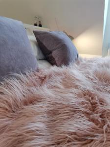 a fur covered blanket on a bed with pillows at The Suffolk Cartlodge 