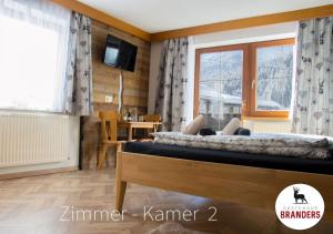 a bedroom with two beds and a tv and a table at Gästehaus Branders in Namlos